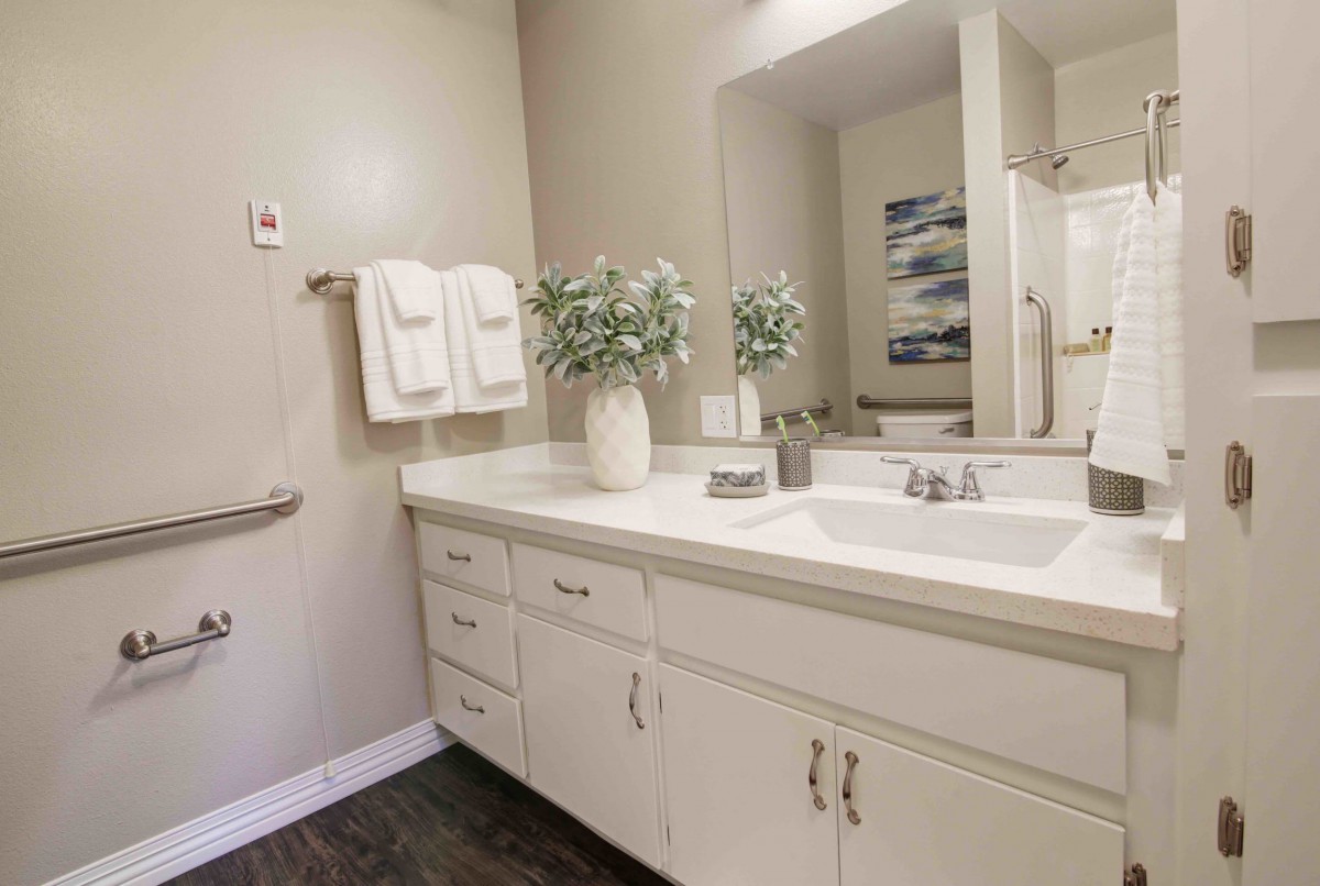 A clean and minimalist bathroom with a white vanity, mirror, and decorative elements.