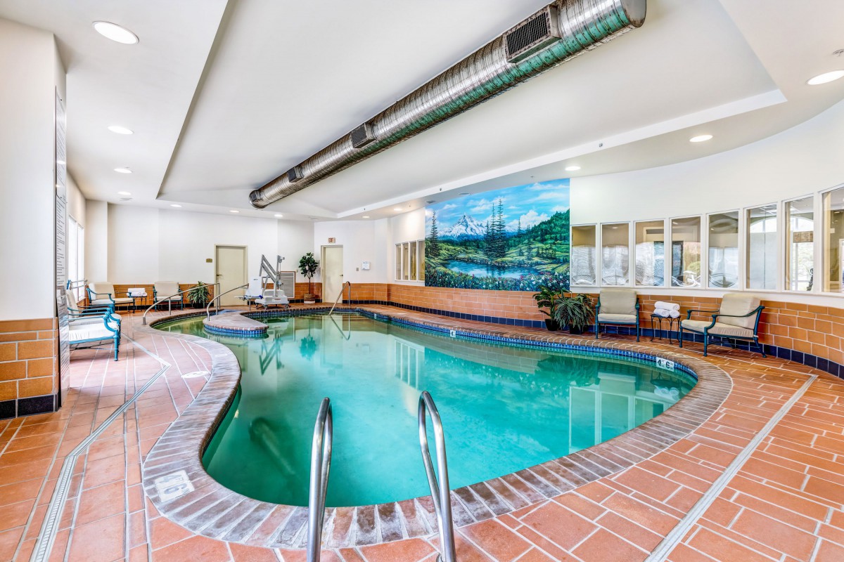 An indoor swimming pool with brick flooring and a large mural on the wall.