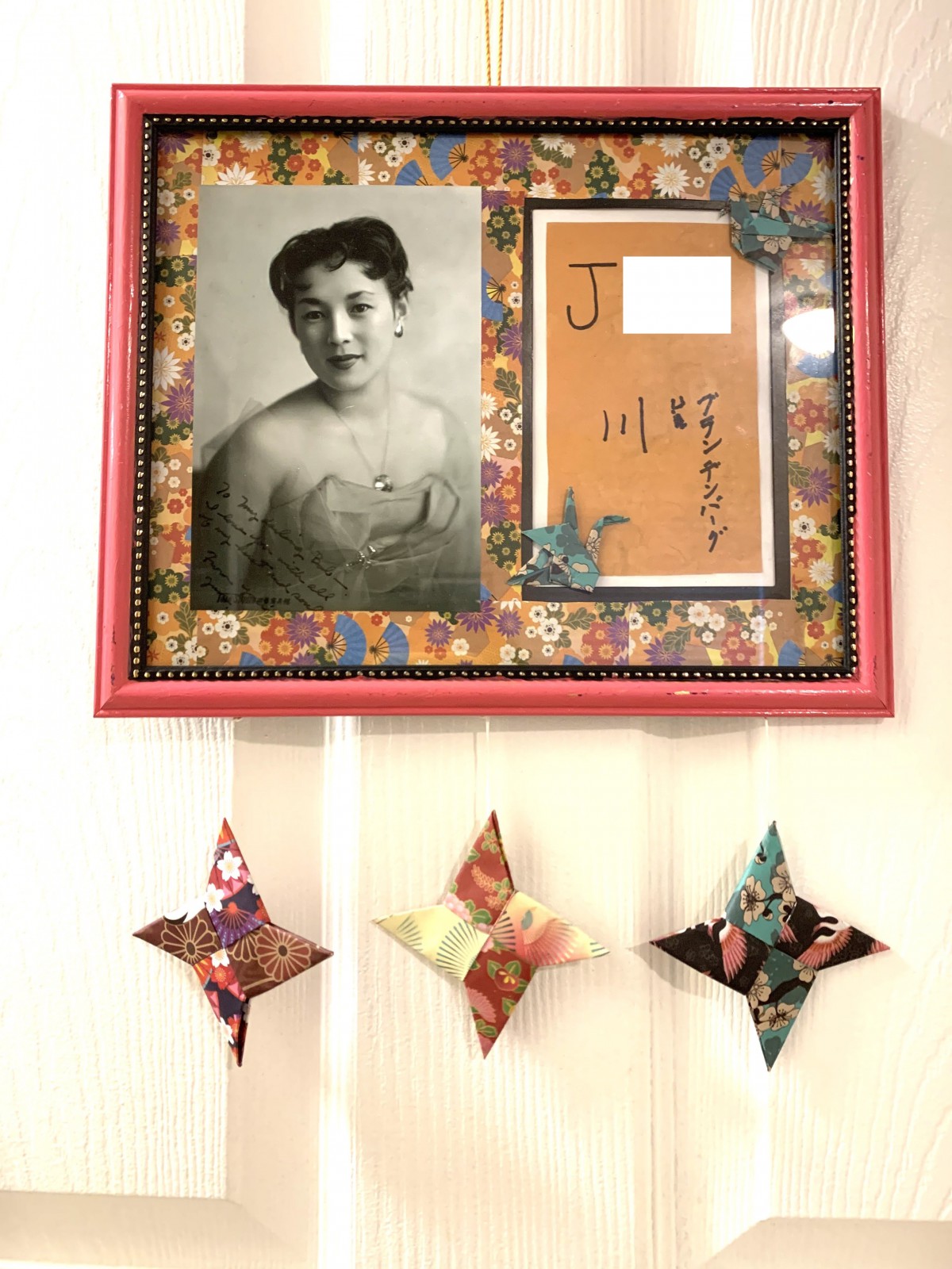 A decorative wall display featuring a framed black and white photograph alongside colorful origami stars.