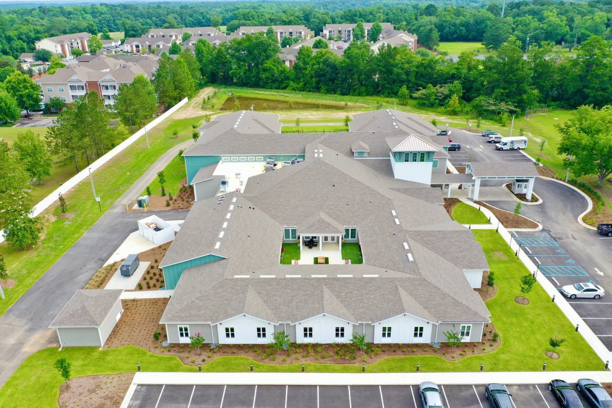 Aerial view of a large building complex surrounded by greenery and parking lots.