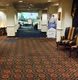 A carpeted hallway with chairs leading to a conference area in a hotel.