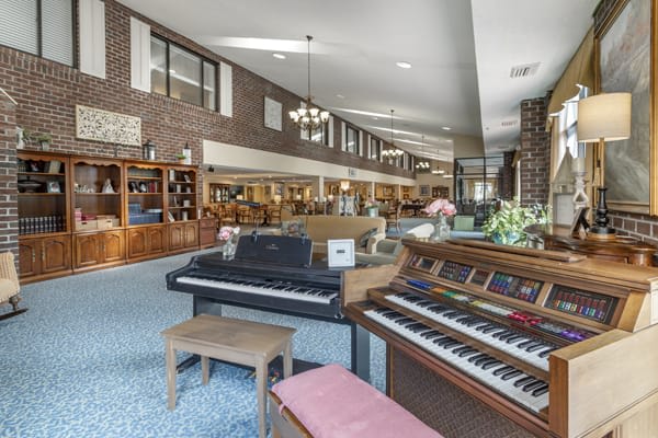 A showroom displaying various musical instruments including a piano and organ, set in a spacious interior with carpeted floors.