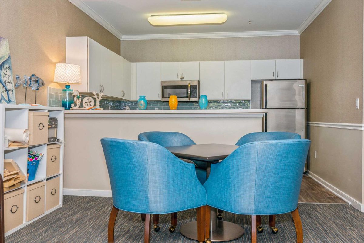 A modern kitchen with stainless steel appliances and a cozy dining area featuring blue chairs.
