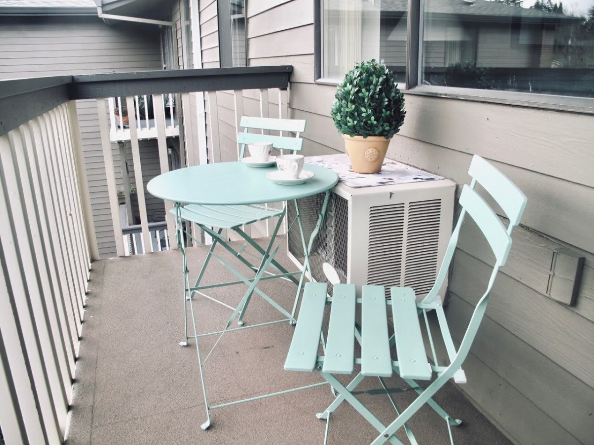A cozy balcony setup with pastel-colored outdoor furniture and a potted plant.