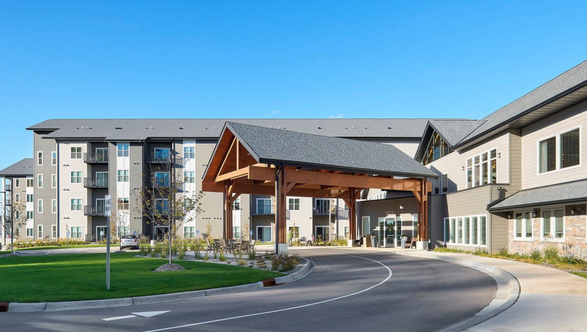 Modern building entrance with a covered driveway and landscaped surroundings.