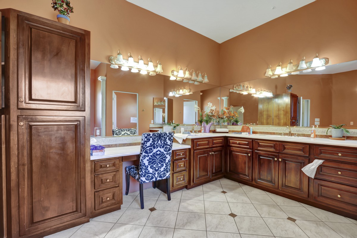 A spacious bathroom featuring a large vanity with multiple mirrors and elegant lighting.
