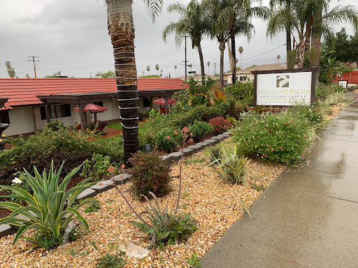 A serene garden area with lush greenery and palm trees, leading up to a hotel entrance.