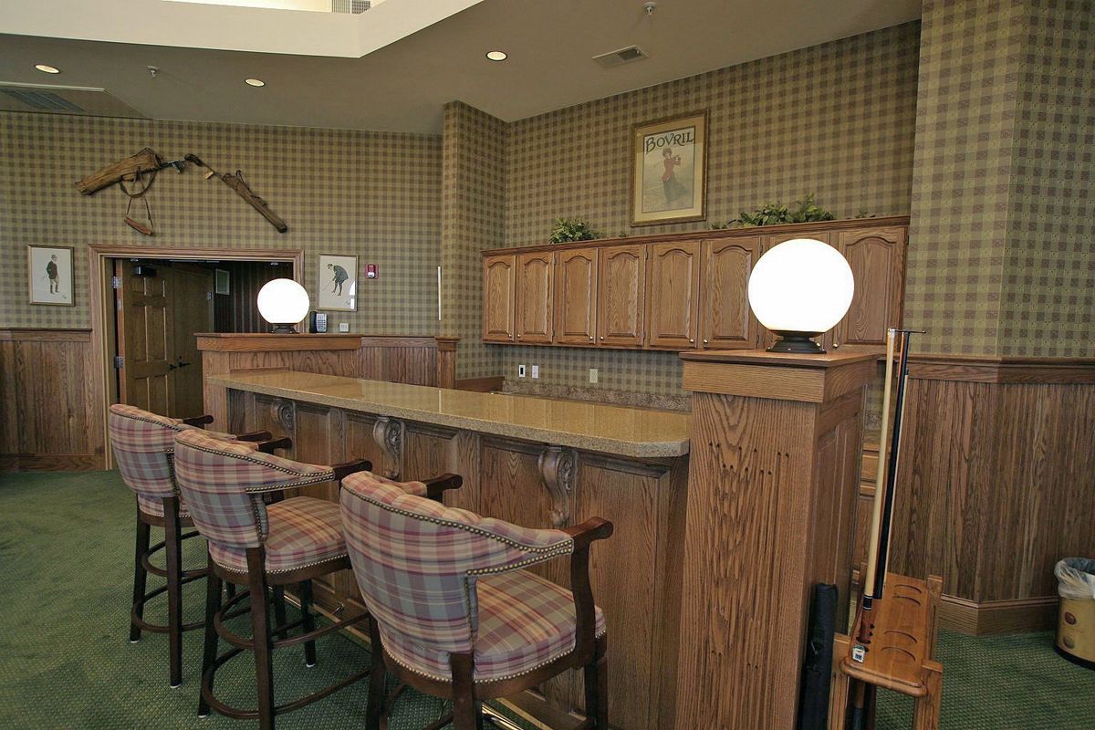 A cozy bar interior with wooden counters and plaid upholstered chairs.