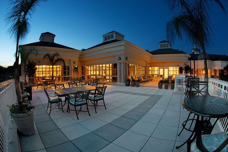 A luxurious outdoor patio area illuminated at night, featuring elegant dining tables and chairs.