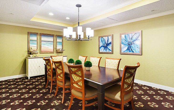 A modern dining room featuring a large wooden table, elegant chandelier, and contemporary artwork on the walls.