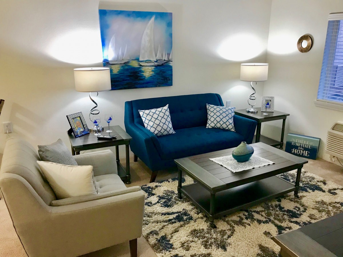 A cozy living room with a blue sofa, stylish artwork, and elegant lighting.