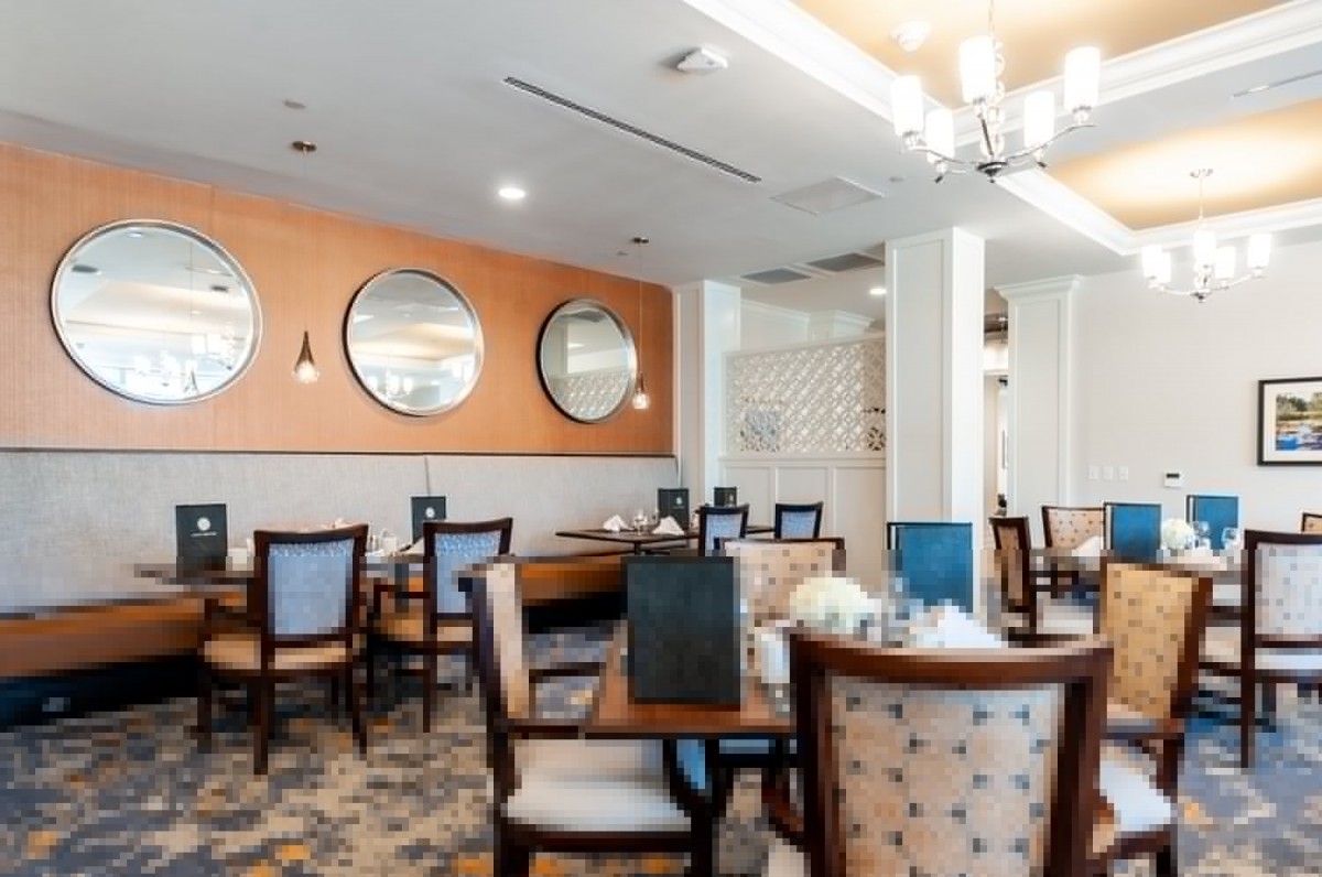 A modern dining area with neatly arranged tables and chairs, decorated with mirrors on the wall.
