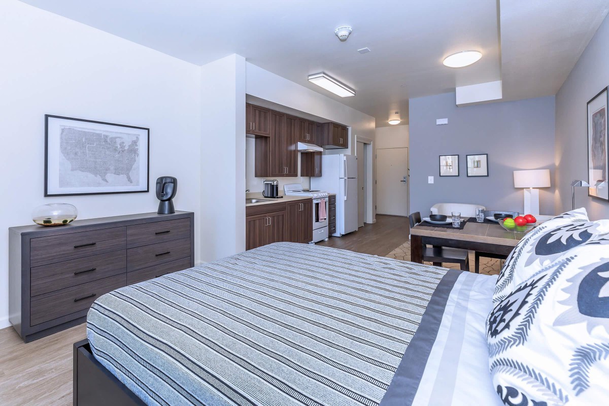 A modern studio apartment featuring a cozy bedroom area and compact kitchenette.