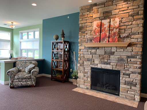 A cozy living room featuring a stone fireplace, stylish shelves, and comfortable seating.