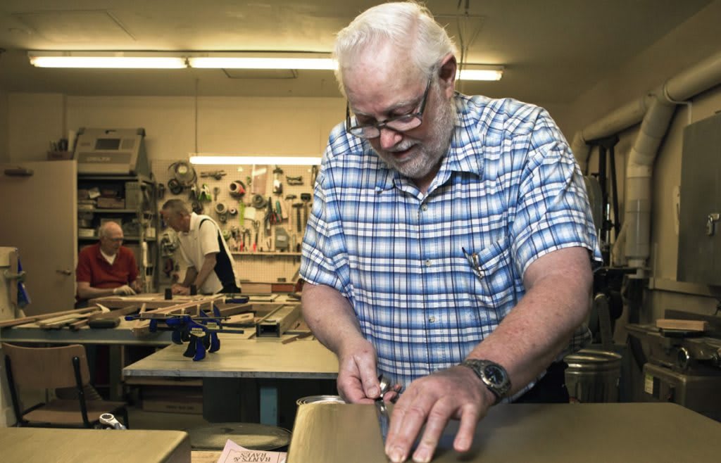 A senior man working on a woodworking project in his workshop.