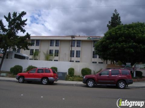 Two cars parked in front of a multi-story building on a cloudy day.