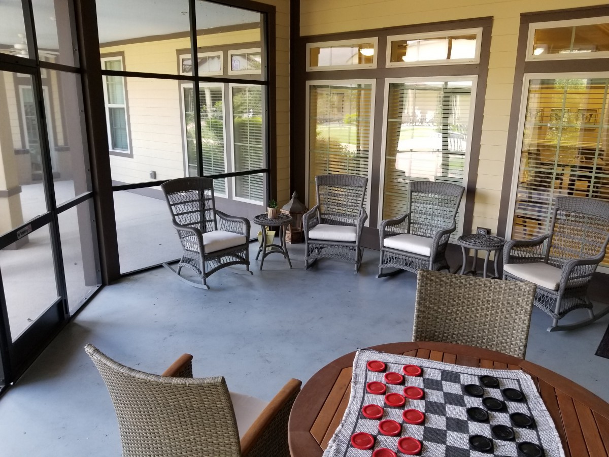A cozy screened porch with seating and a chessboard on the table.