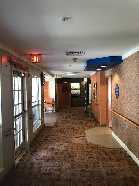 A well-lit hotel corridor with exit signs and multiple doors.