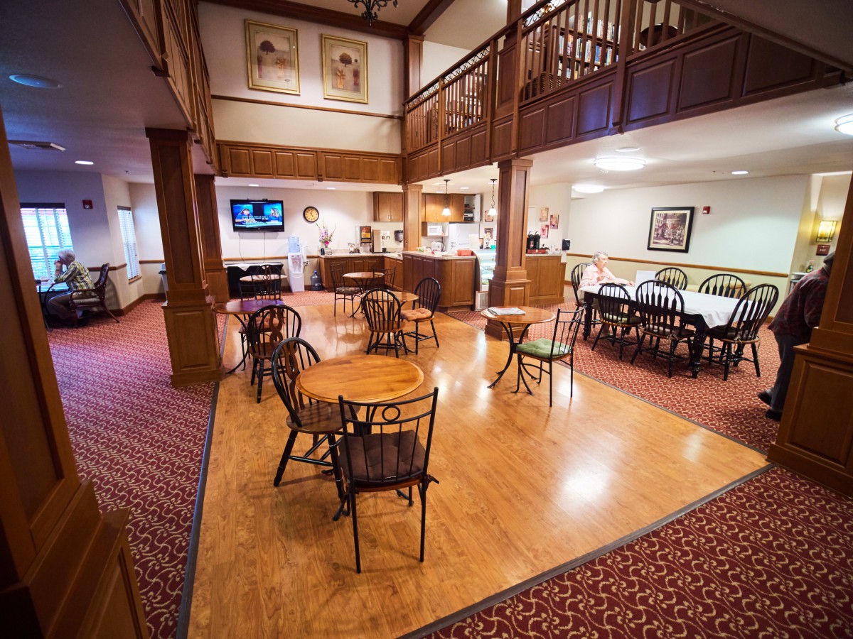 A cozy caf interior with wooden floors, tables and chairs, and a bar counter.