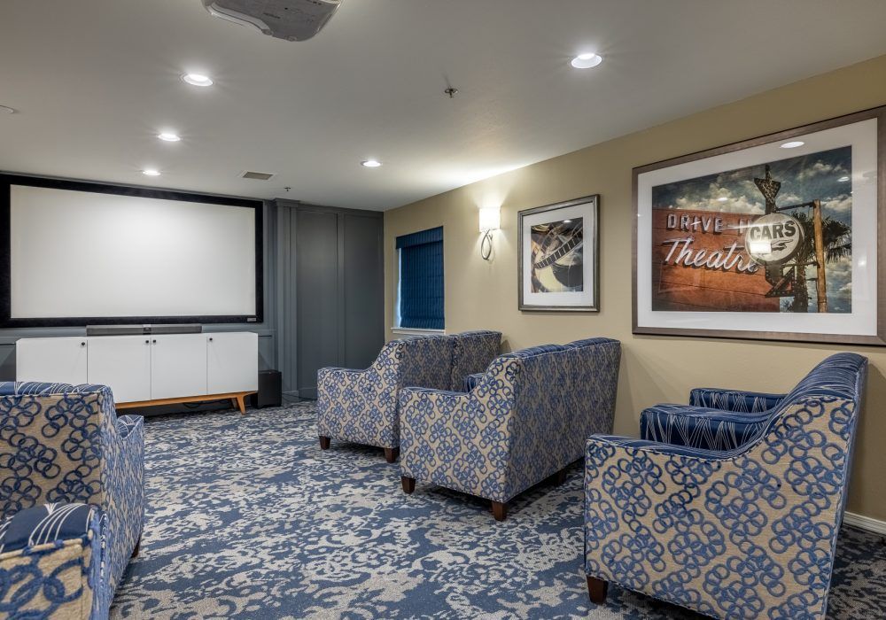 A cozy home theater room with patterned seating and a large screen.