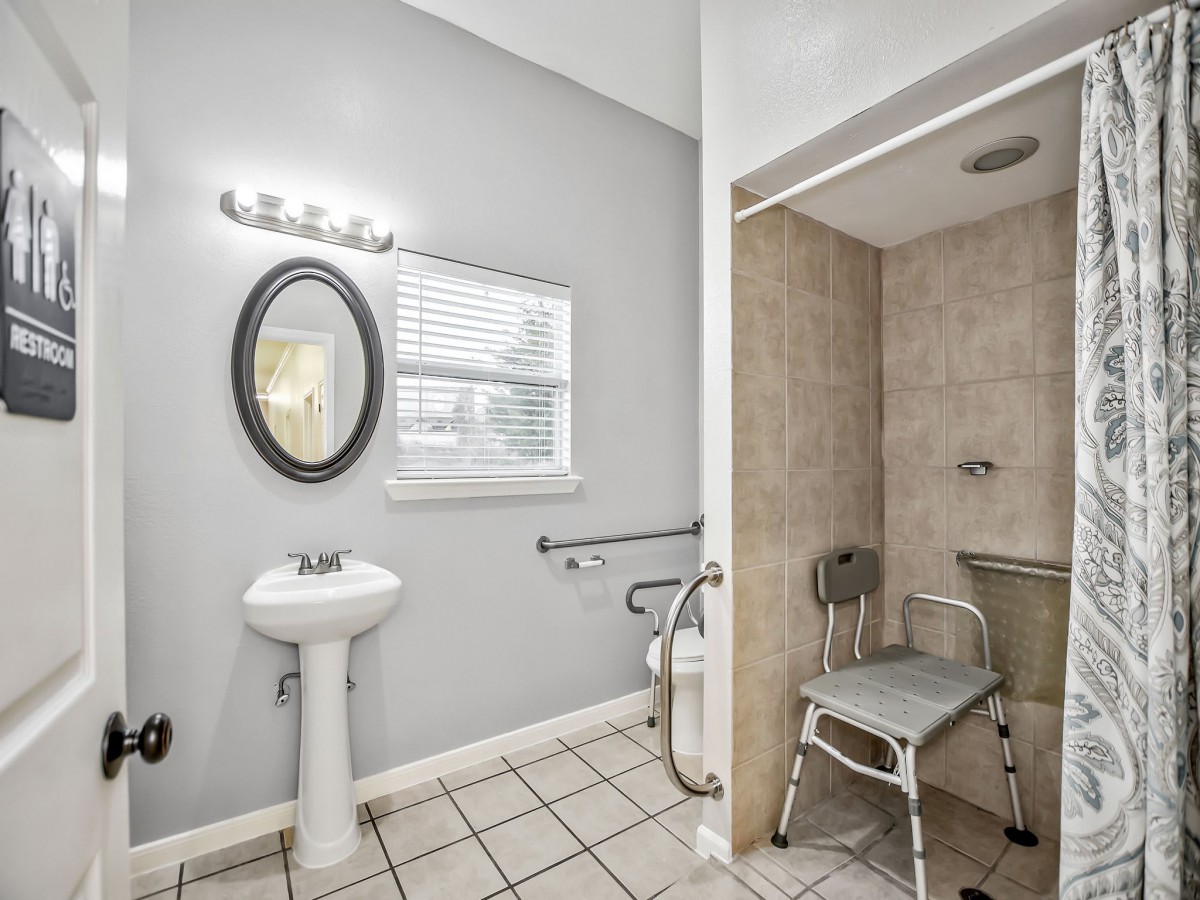 An accessible bathroom with a shower, sink, and grab bars.