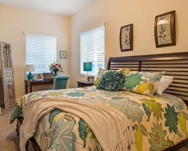 A well-decorated bedroom with a colorful bedspread, soft lighting, and cozy furnishings.