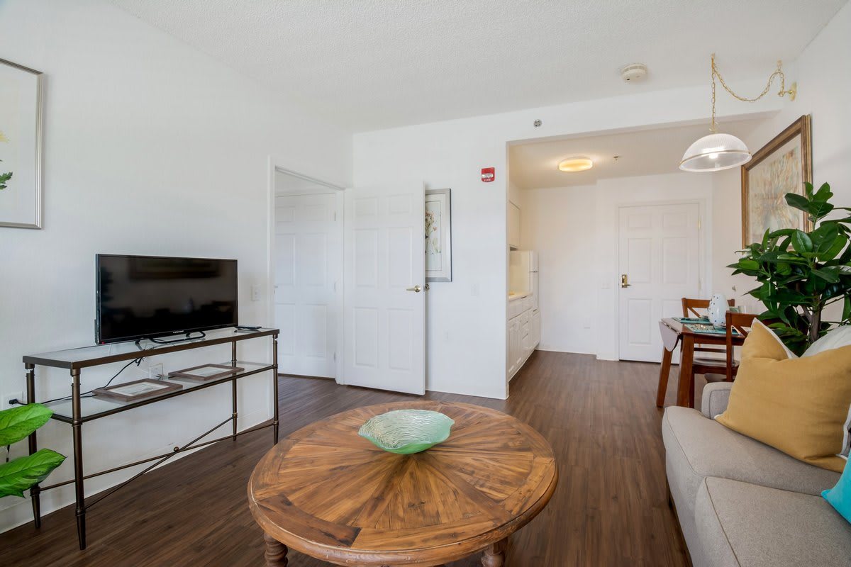 A modern living room with a wooden coffee table, flat-screen TV, and cozy seating area.
