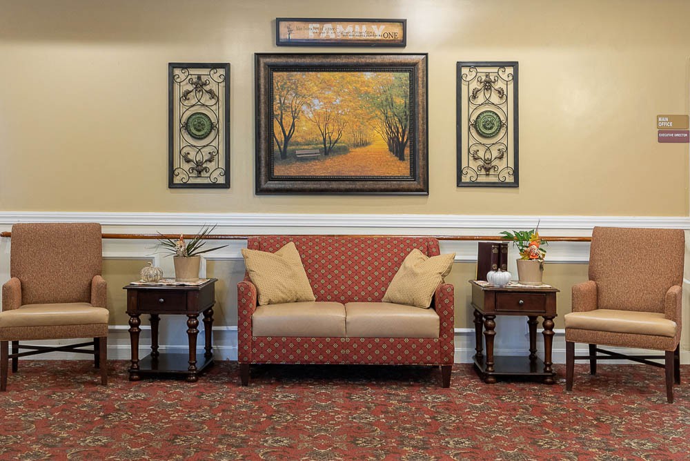 A cozy living room with a red patterned sofa, artwork on the wall, and side tables.