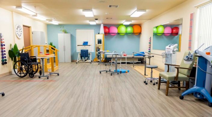 A well-equipped physical therapy and rehabilitation room with exercise equipment and gym balls.