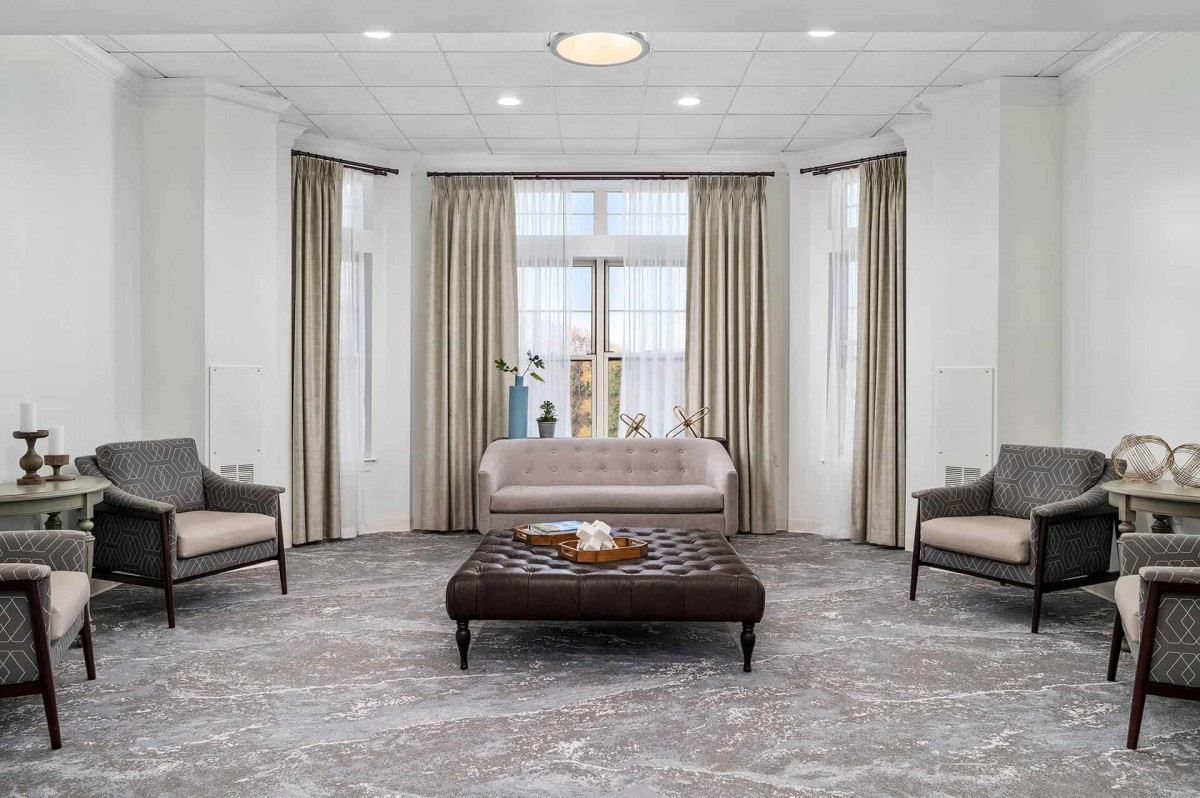 A modern living room with neutral tones, featuring a sofa, armchairs, and a central coffee table.