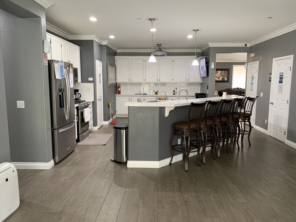 A modern kitchen with a spacious layout, featuring a large island with bar stools and sleek appliances.