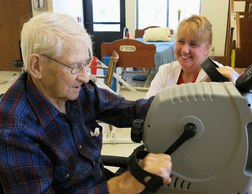 An elderly man engages in exercise with the support of a healthcare professional, promoting physical rehabilitation.
