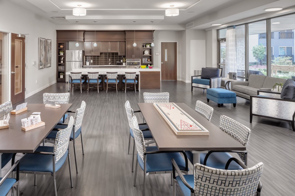 A modern common area with a kitchen and dining setup, featuring sleek furniture and an open layout.