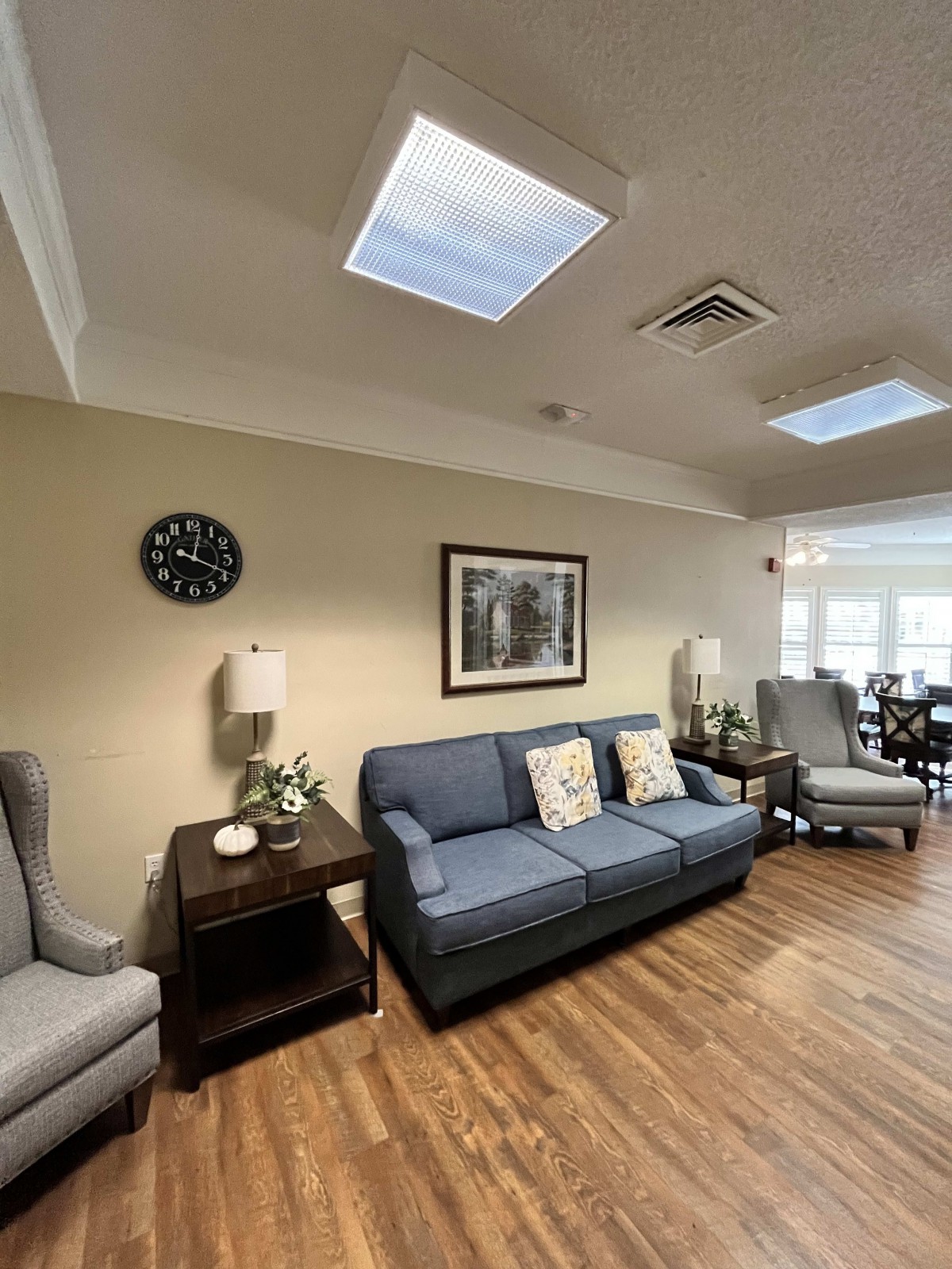 A cozy living room with a blue sofa, armchairs, and decorative elements.