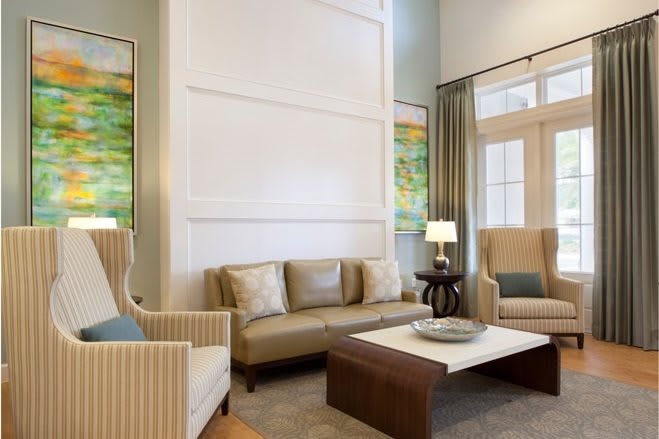A modern living room with elegant furnishings, including a sofa, armchairs, and a coffee table, complemented by artwork and lighting.