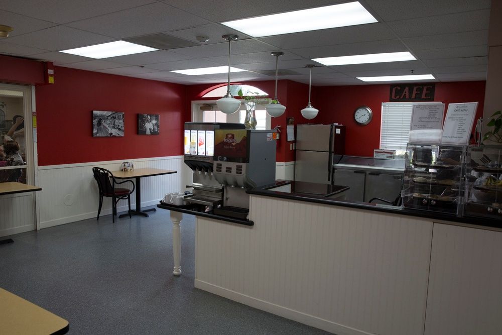 Interior view of an empty restaurant with red walls and a modern kitchen setup.