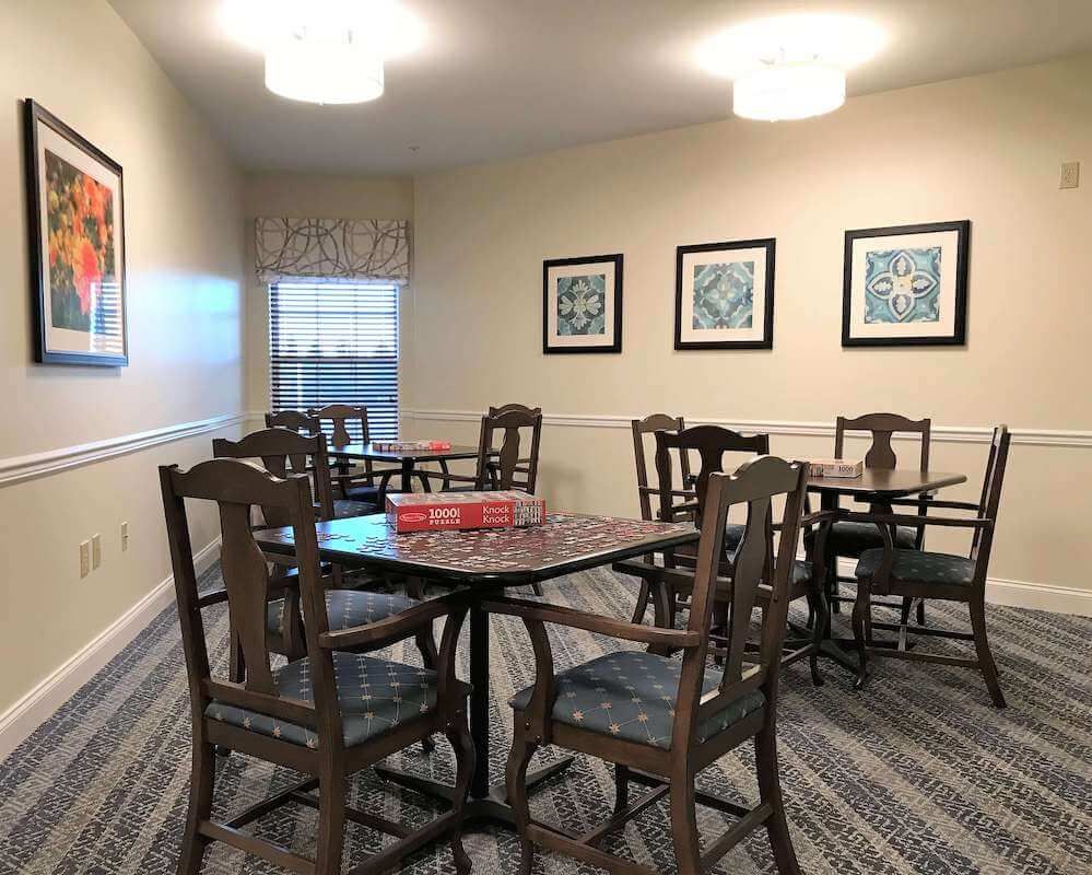 A cozy dining room with tables and chairs, featuring framed artwork on the walls.