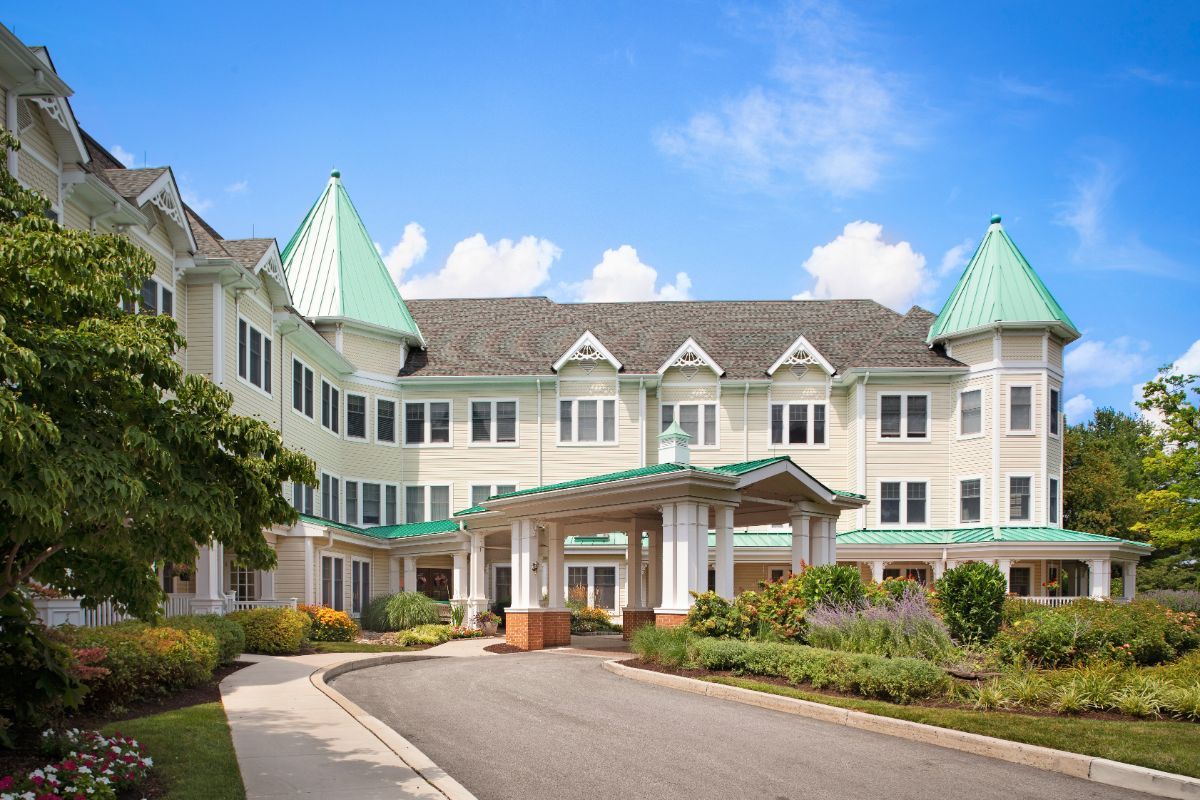 A large residential building with a grand entrance and manicured landscaping on a sunny day.