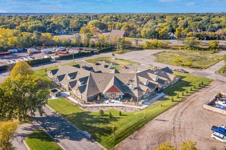 Aerial view of a uniquely-shaped building surrounded by lush greenery and a parking lot.