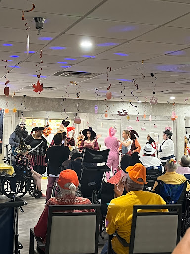 A lively performance engaging residents at a senior living community, filled with colorful costumes and festive decorations.