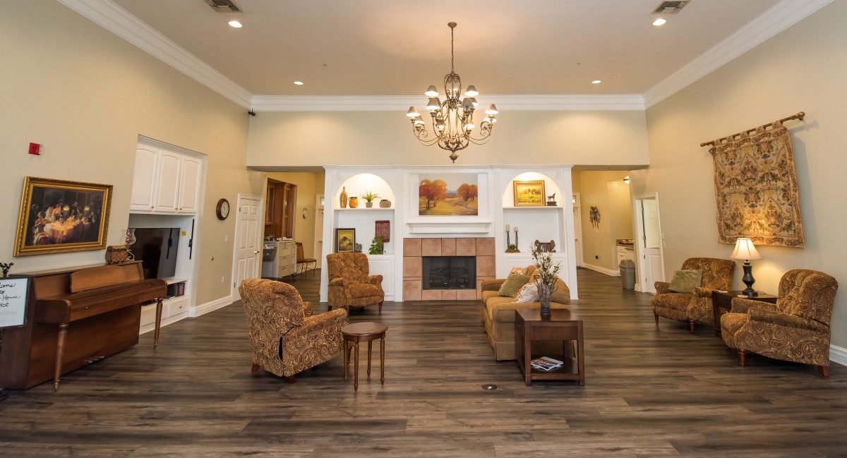 A spacious living room featuring a chandelier, comfortable armchairs, and a fireplace.