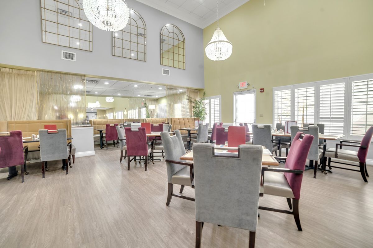 A bright and spacious restaurant dining area with elegant chandeliers and neatly arranged tables and chairs.