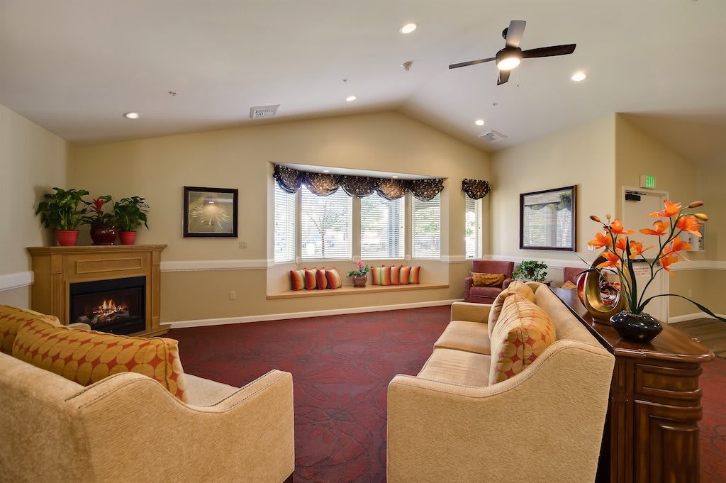 A cozy living room with sofas, a fireplace, and large windows.