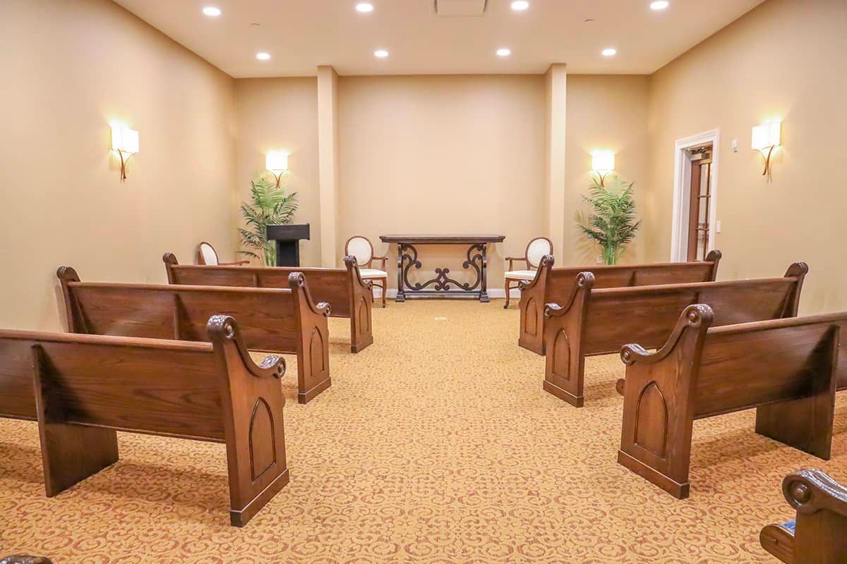 A small chapel setup with rows of wooden pews and elegant decor.