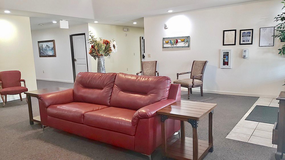 A cozy living room with a red leather sofa, chairs, and decorative elements.