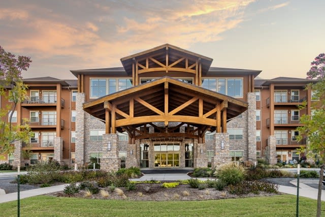 A modern building with a wooden entrance and landscaped surroundings.