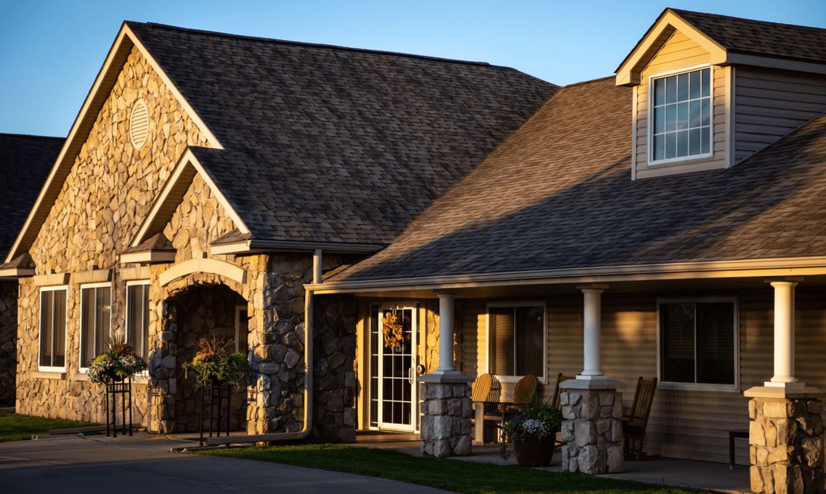 A beautiful residential house with a stone exterior and a welcoming porch in the warm glow of sunlight.