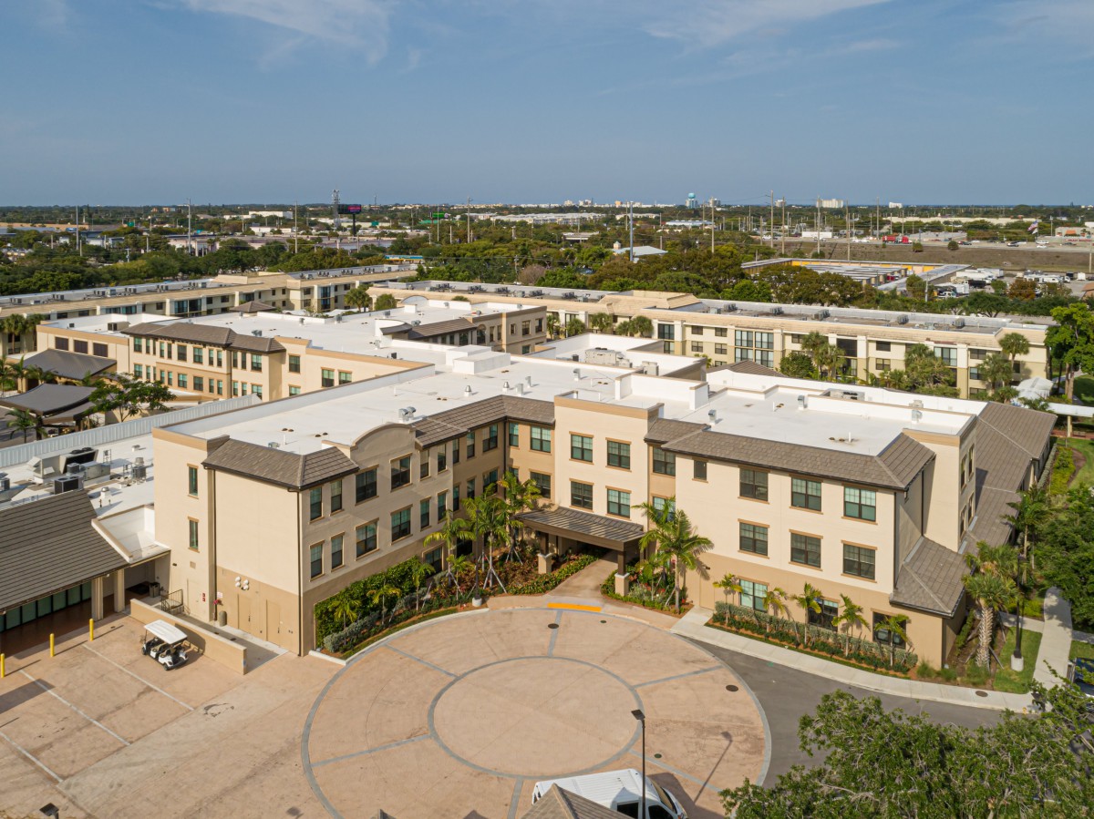 Aerial view of a large building surrounded by greenery in a suburban area.