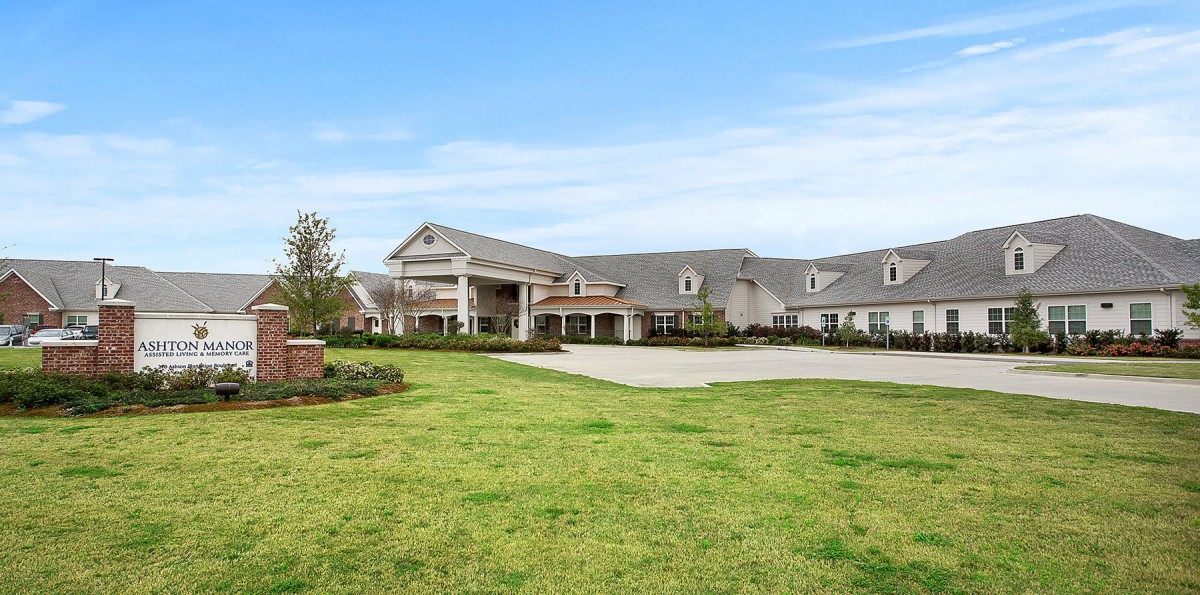 A large mansion with a neatly trimmed lawn under a clear blue sky.