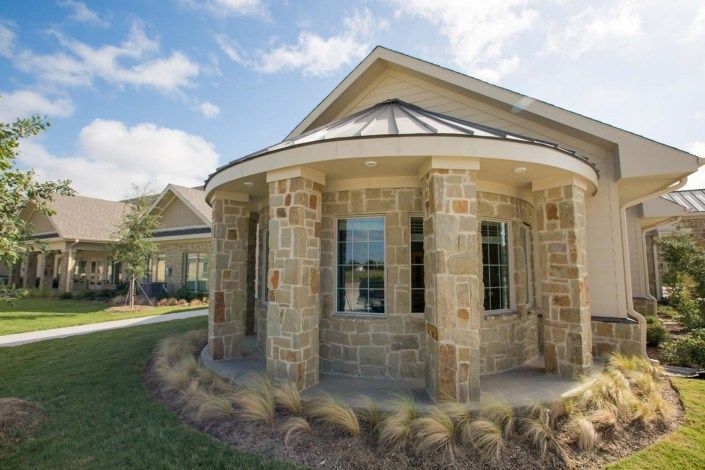 A stone house with columns under a clear blue sky.
